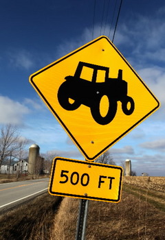 Caution and keep a 500 foot distance between yourself and the farm vehicle ahead of you.